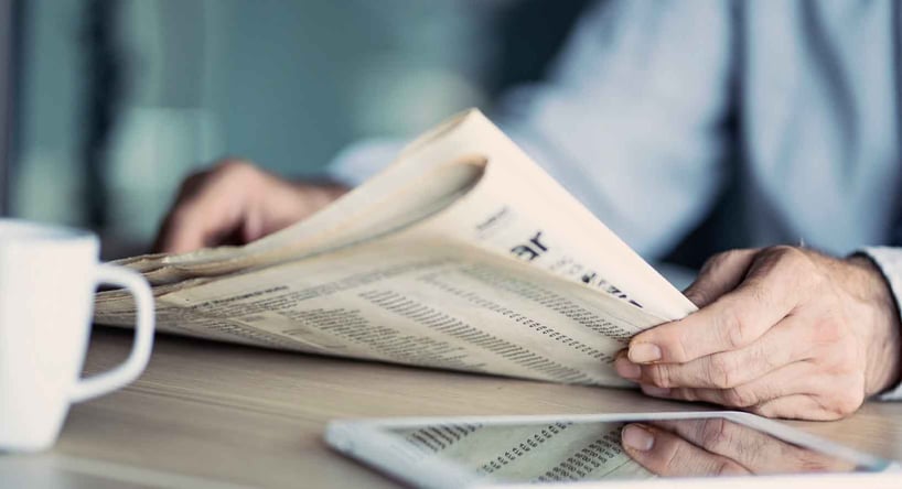 Man reading newspaper about international market trends.