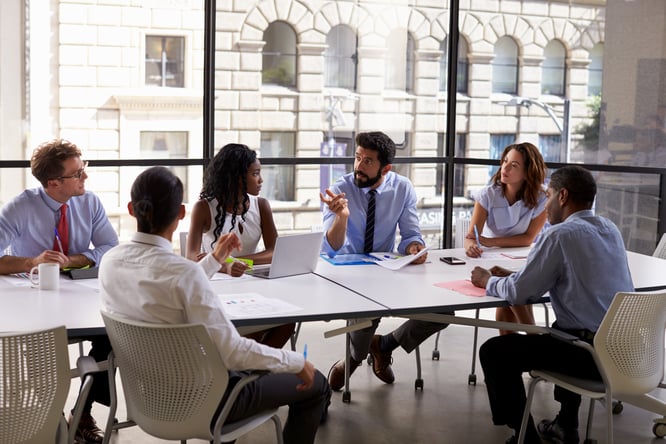 Diverse team of business professionals discussing corporate divestitures.