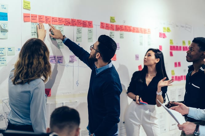 Skilled workers reading post-it notes on a whiteboard. 